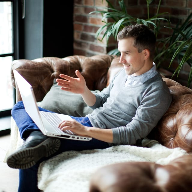 Adult learner sitting on a couch using a laptop for a Berlitz private online Mandarin lesson.